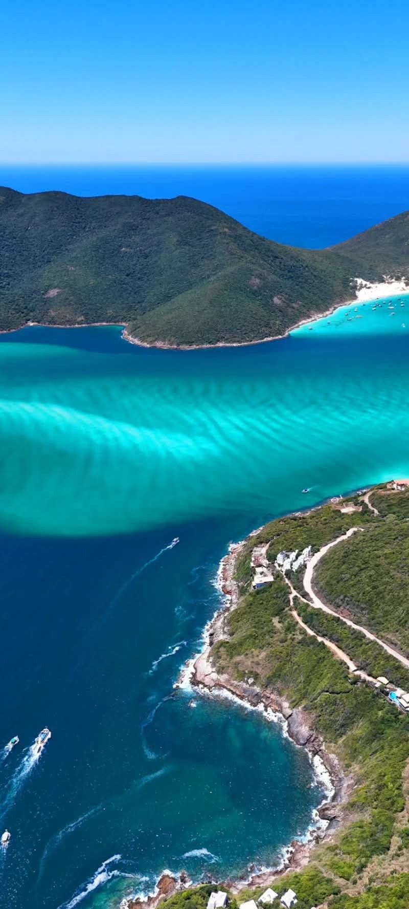 Praia de água azul-turquesa com barcos em Arraial do Cabo