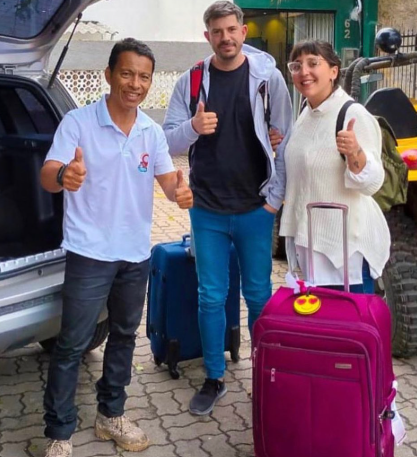 Passageiros sorrindo ao lado de um veículo